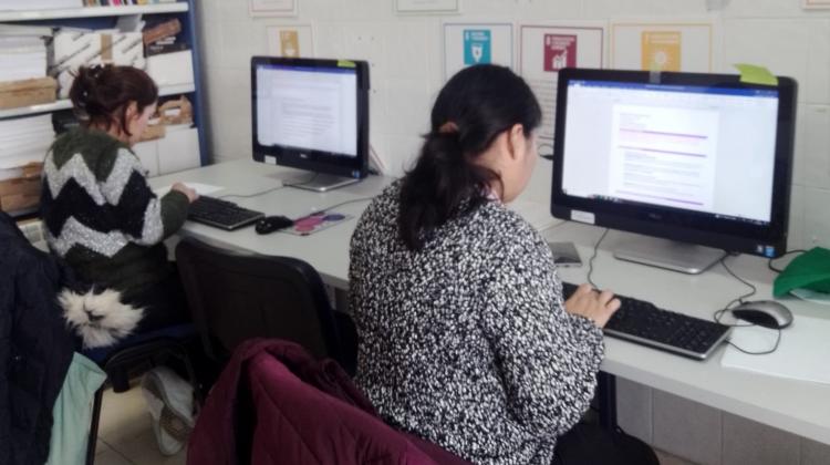 Dos mujeres sentadas cada una delante de un ordenador trabajando