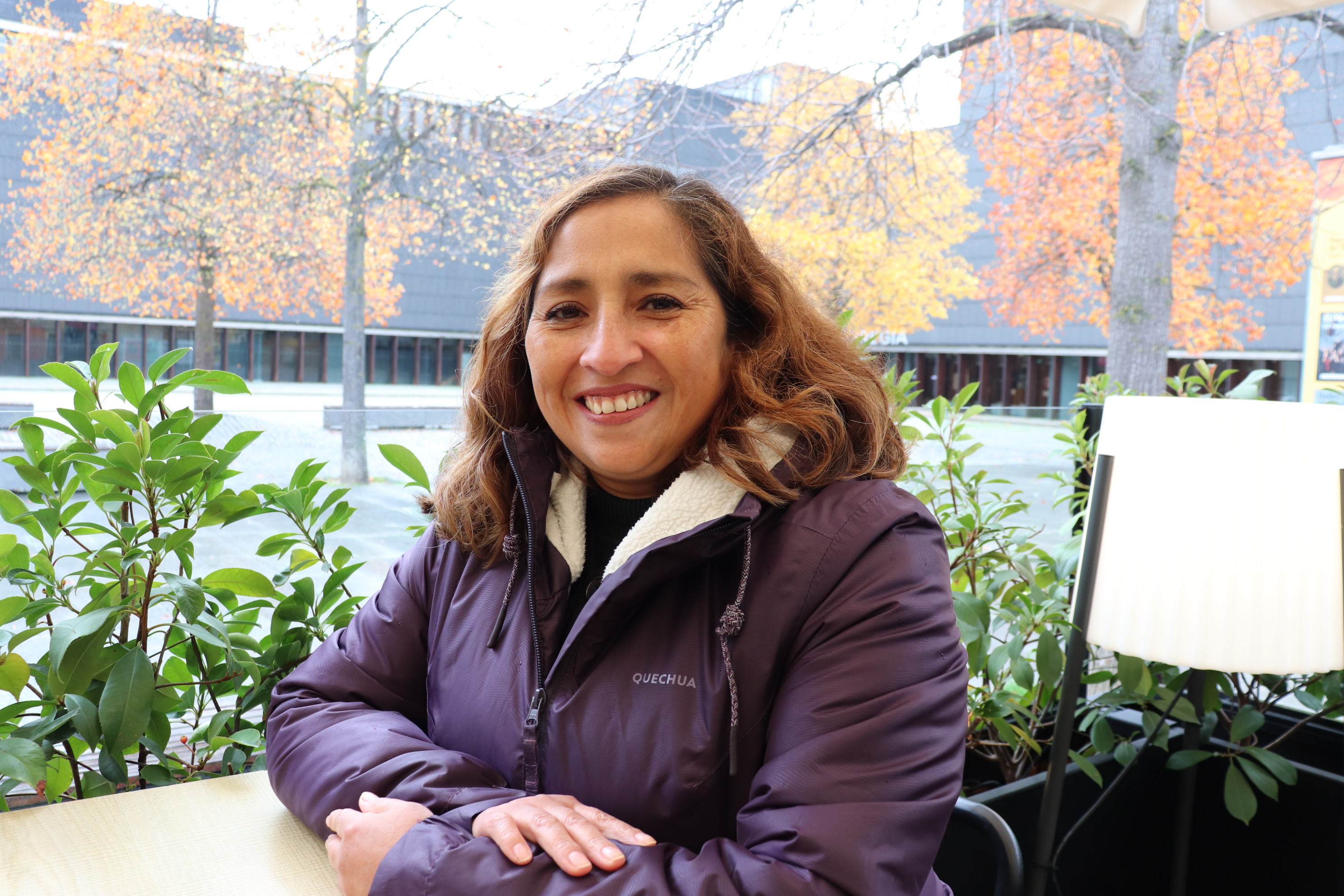 Rocío sentada en una mesa de una terraza de un bar mirando a cámara sonriente