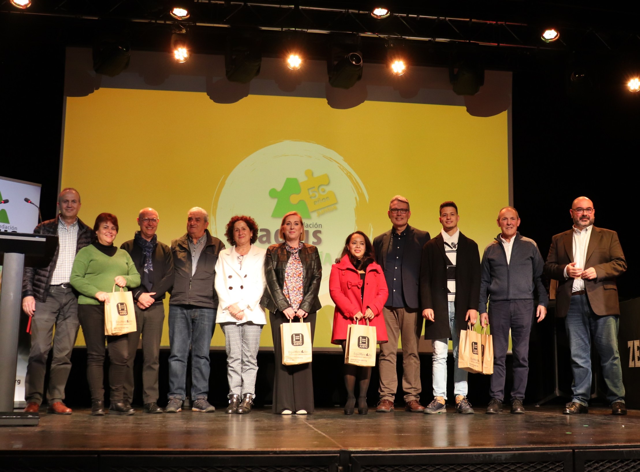 Un grupo de personas posando encima de un escenario. De fondo, el logotipo del 50 aniversario de Fundación Santa Lucía Adsis