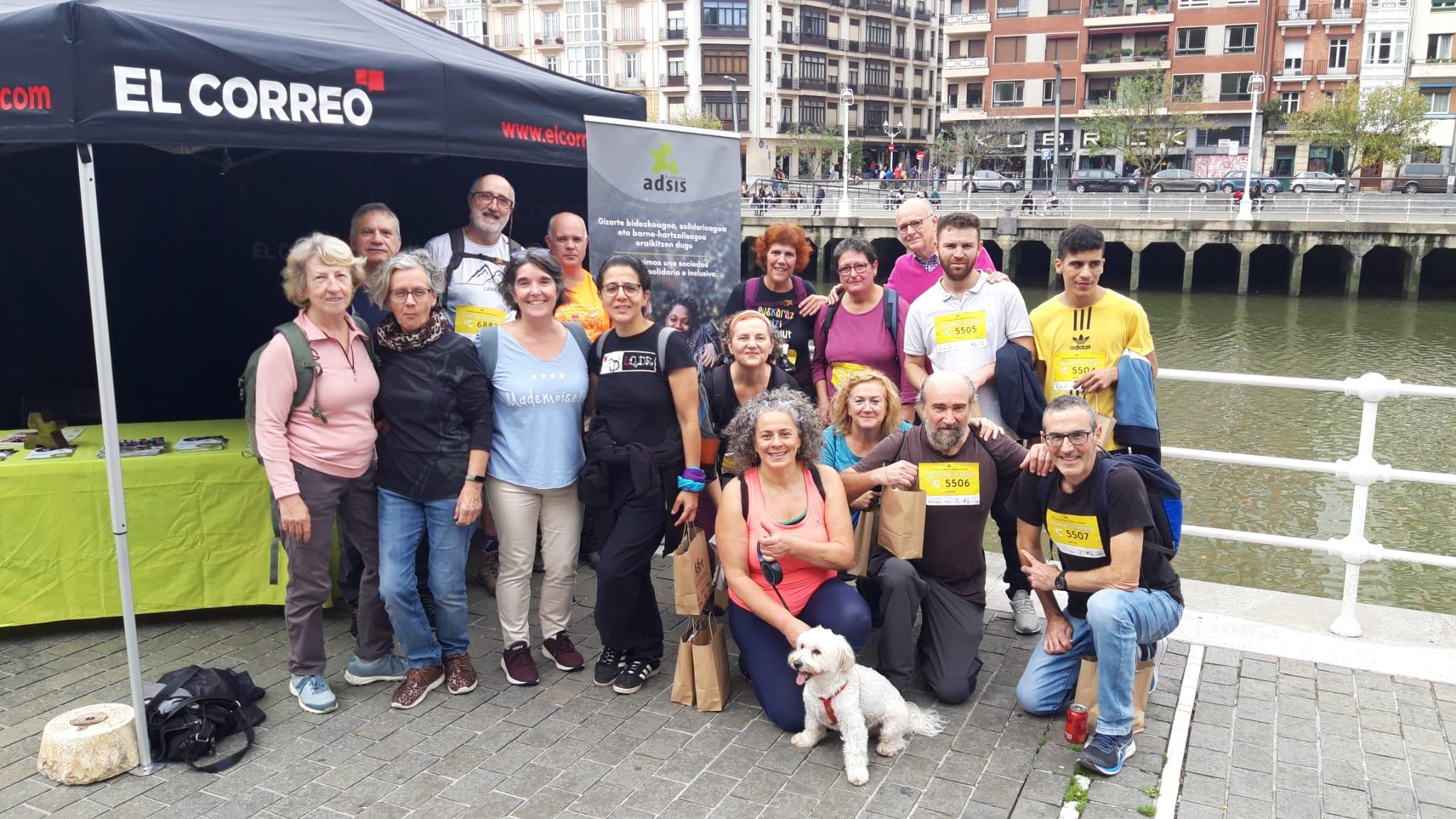 Un grupo de gente posando delante de un stand de El Correo y Fundación Adsis