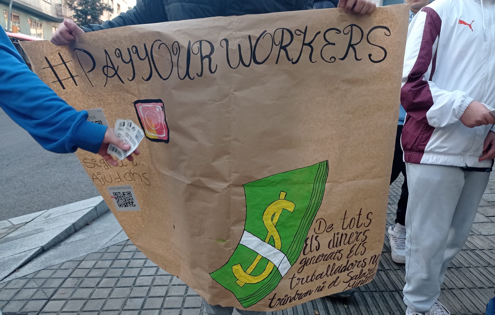 Pancarta en la que se lee "pay your workers"