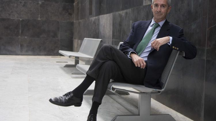 Santiago Quiroga vestido con traje y sentado en una silla, mirando a cámara de lado.