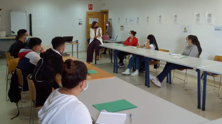 Un grupo de jóvenes sentados en una aula escuchando a una mujer que les explica algo