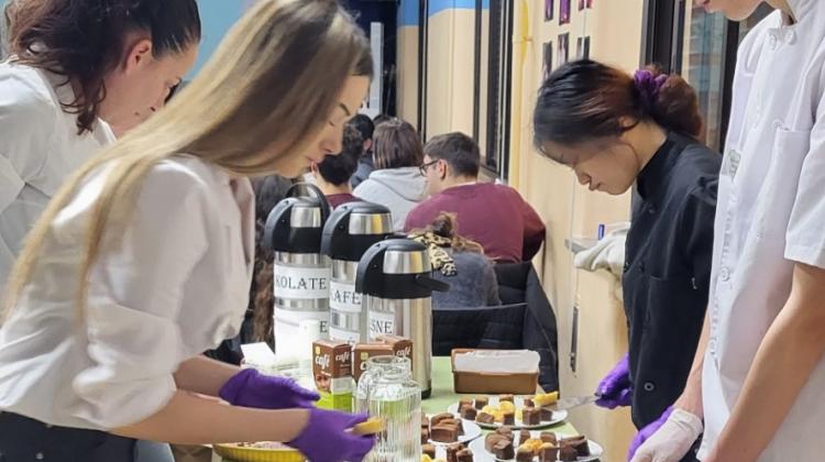 Grupo de cuatro chicos y chicas sirviendo diversos platos en una mesa