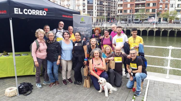 Un grupo de gente posando delante de un stand de El Correo y Fundación Adsis