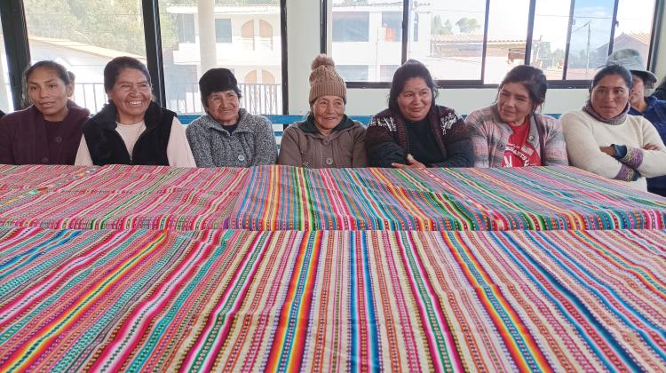 Un grupo de mujeres campesinas de Junin sentadas en una mesa mirando a cámara