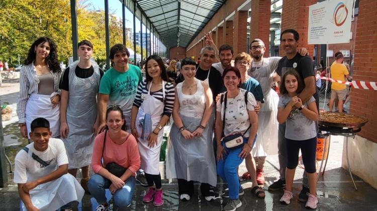 Un grupo de jóvenes vestidos con delantal posando con una paella 