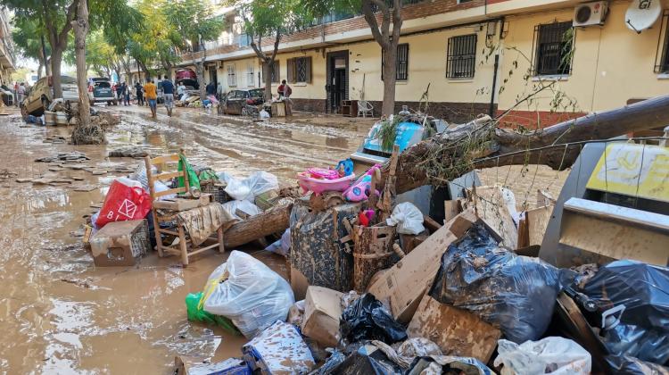 Imagen de una calle de casa bajas con el pavimento cubierto de barro y en primer plano una pila de basura y escombros también con barro
