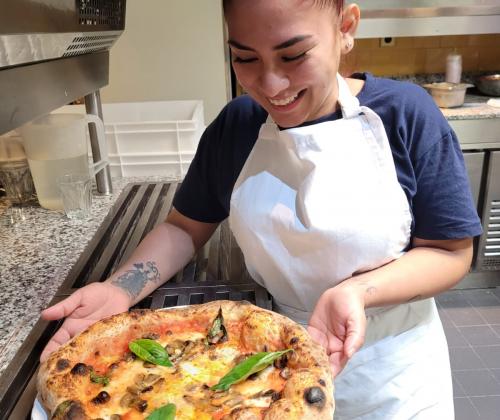 Una chica mostrando una pizza terminada