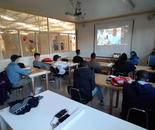 Un grupo de jóvenes sentados en una aula atendiendo a una preesntación que se proyecta en la pantalla